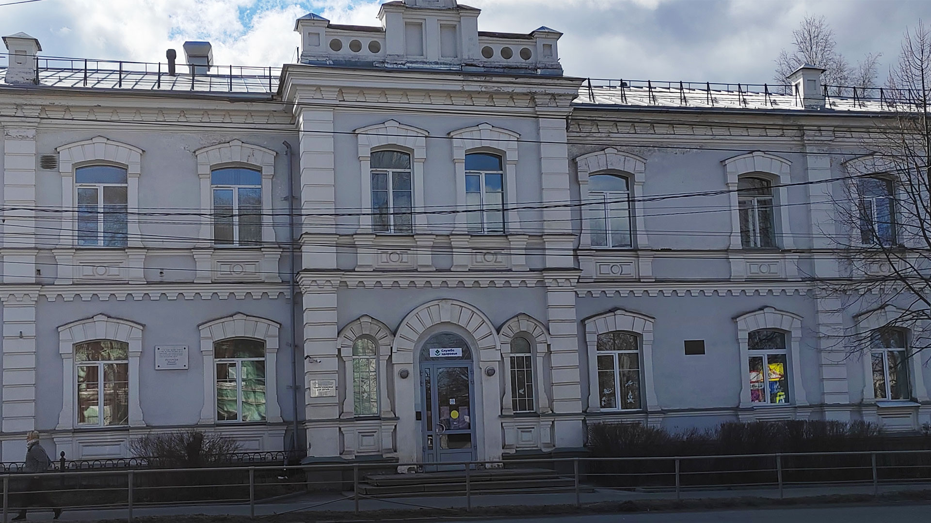 Двухэтажное каменное здание серого цвета со входом в центральной части.