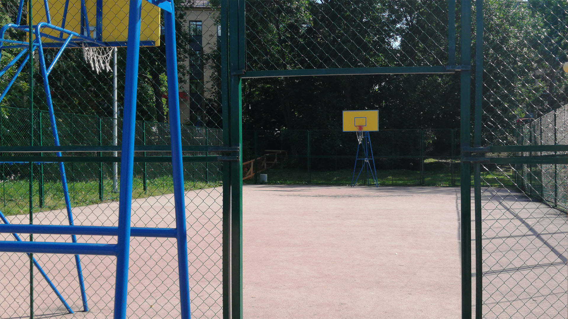 Огороженная сеткой площадка с баскетбольными кольцами.