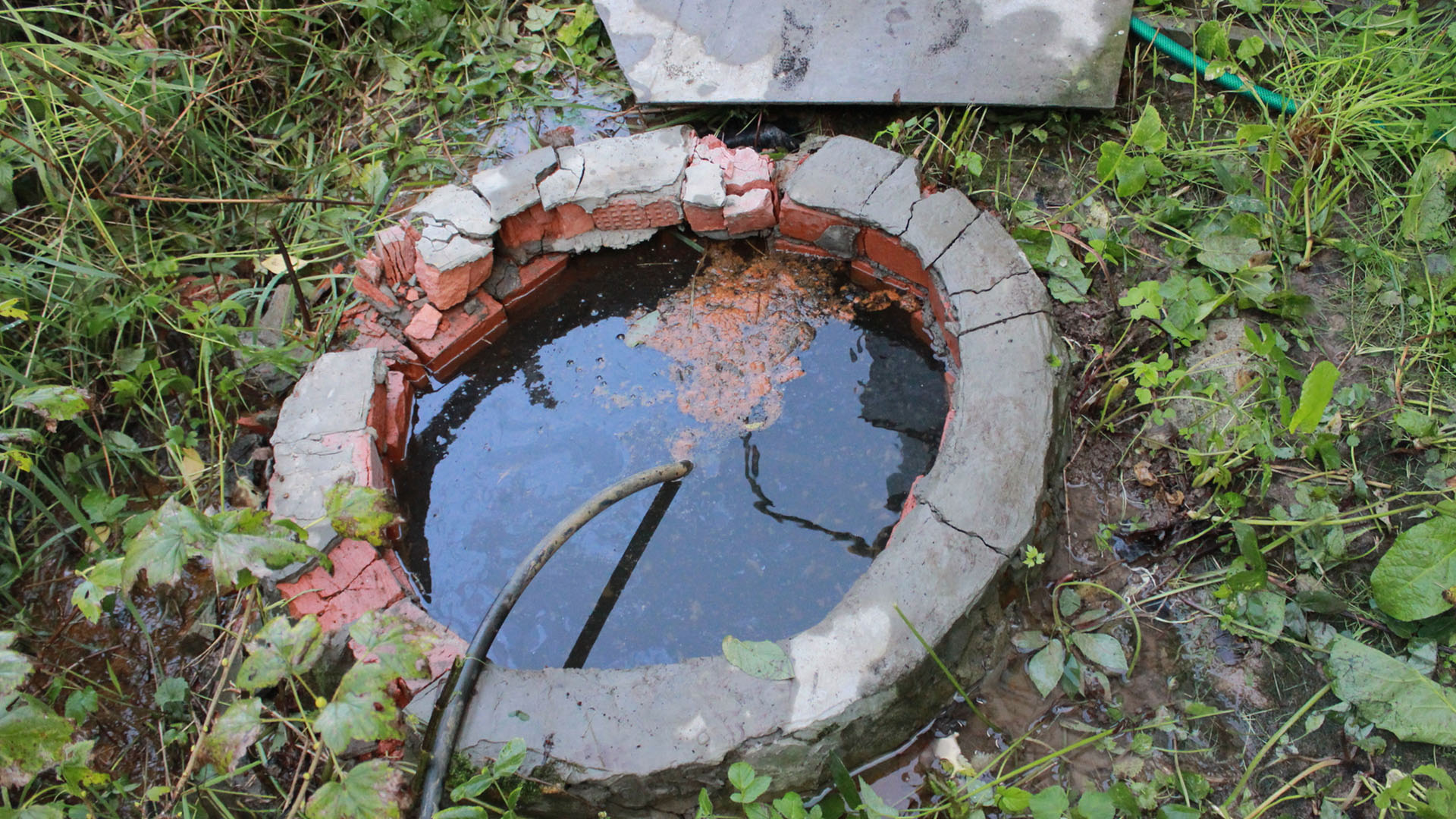 Круглая яма обложенная кирпичом заполнена водой.