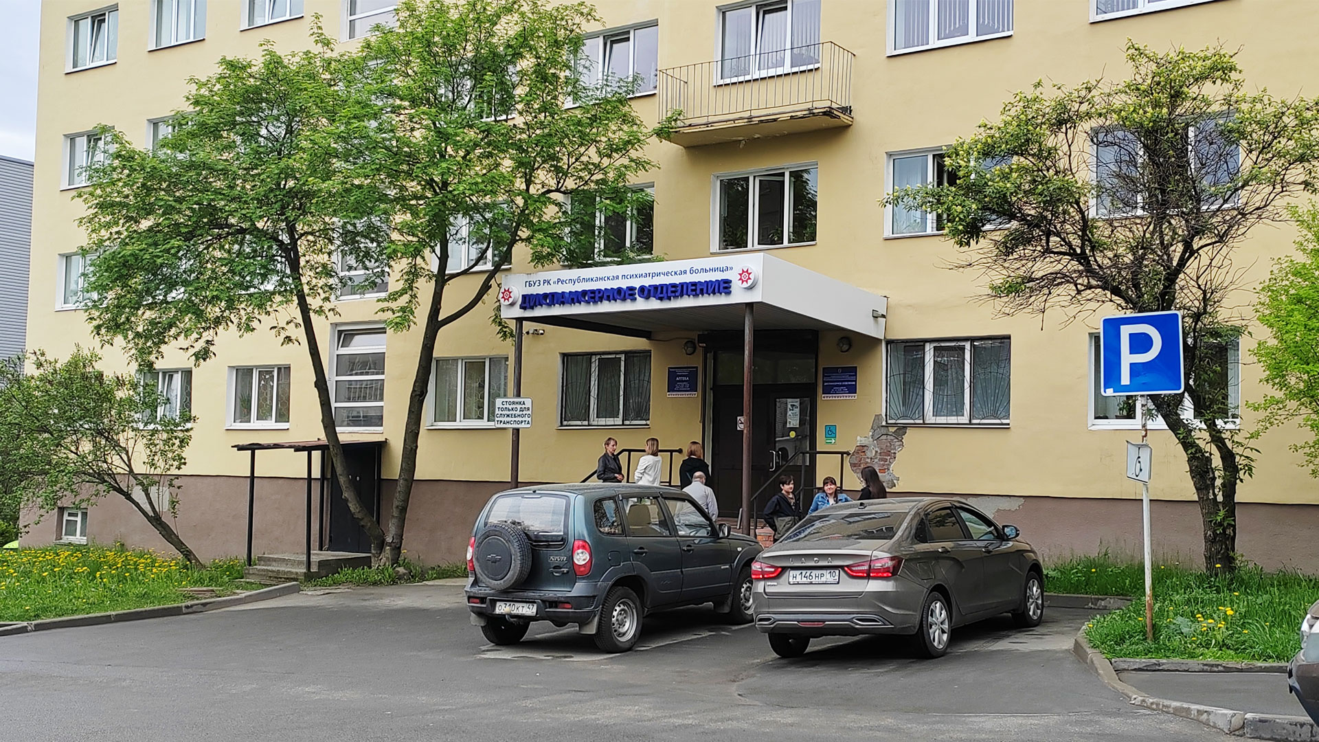 Административное здание медицинского учреждения с парковкой перед входом.