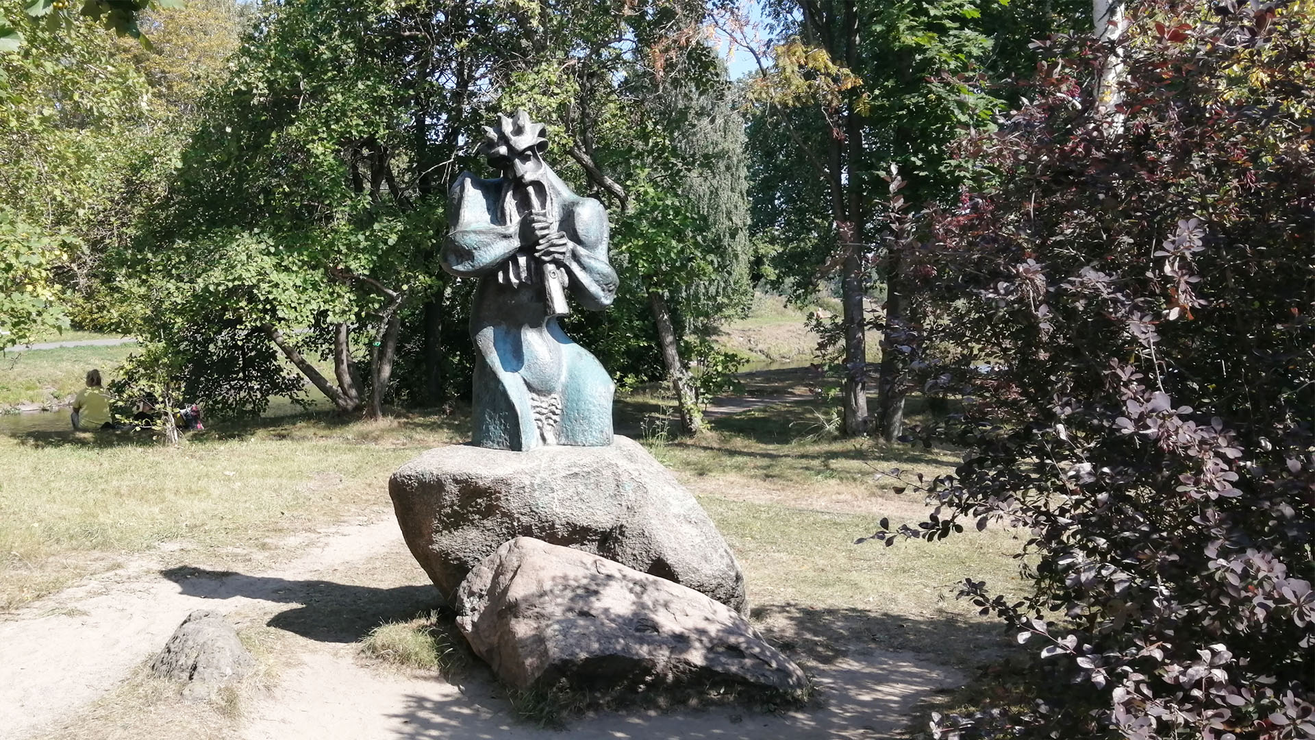 Скульптура лесного бога играющего на дудочке установлена на камне-валуне.
