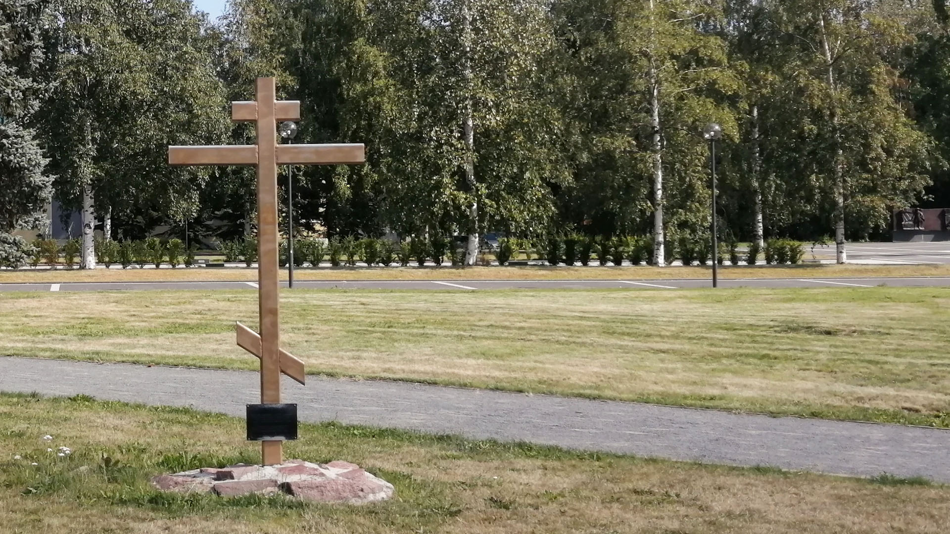 Крест с памятной табличкой на каменном основании.